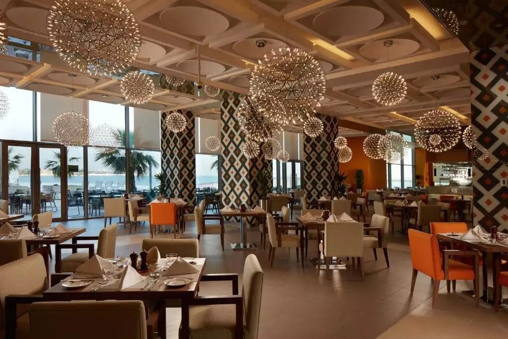 Un ristorante del Royal M Hotel, Abu Dhabi, con lampadari a soffitto.