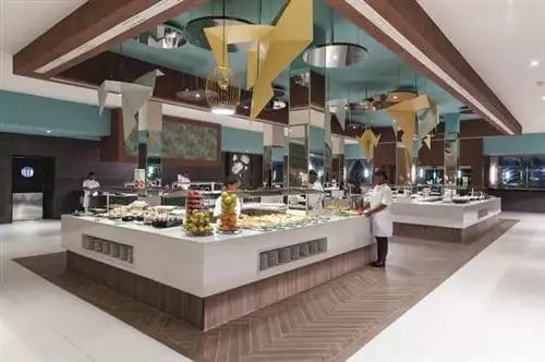 Buffet moderno presso il RIU Cabo Verde Hotel con decorazioni pendenti artistiche e uno chef presente alla postazione di ristorazione.