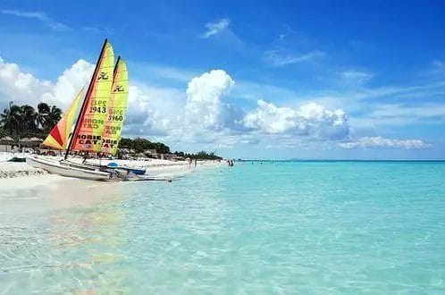 Una colorata barca a vela ormeggiata sulla spiaggia tropicale di Varadero con cieli azzurri e calme acque turchesi.