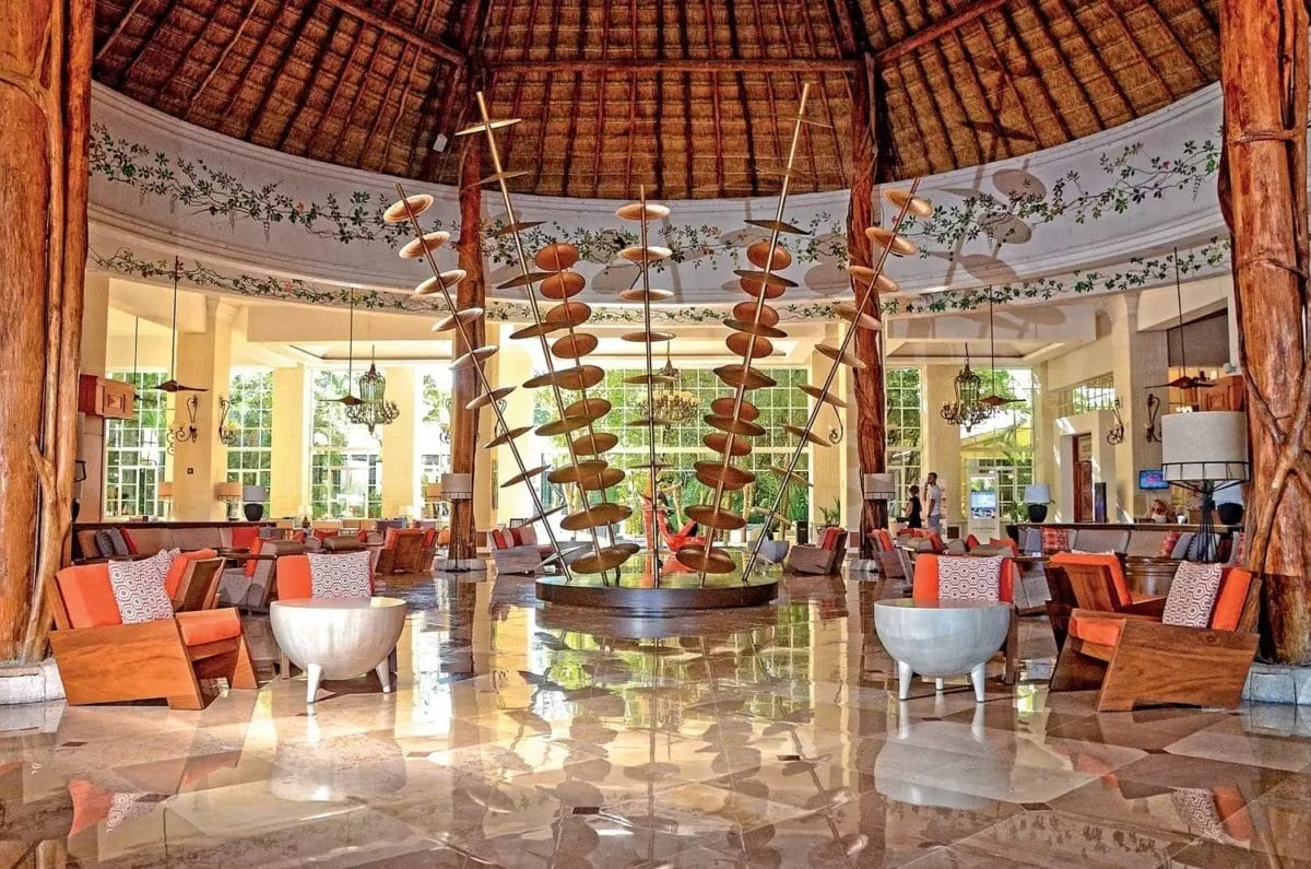 Elegante lobby del resort con un grande lampadario, elementi architettonici tropicali e una serie di posti a sedere nel Royal Tulum.