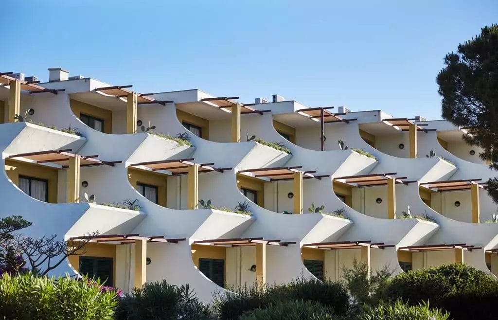 Moderni appartamenti per vacanze a schiera con balconi curvi immersi nel verde lussureggiante sotto un cielo azzurro e limpido al VOI Tanka Resort.