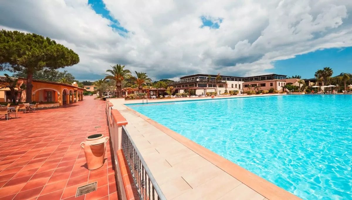 La tranquilla piscina del VOI Tanka Resort si crogiola sotto un cielo azzurro, fiancheggiata da lettini e da un'architettura in stile mediterraneo, invitando gli ospiti a un tuffo rinfrescante.