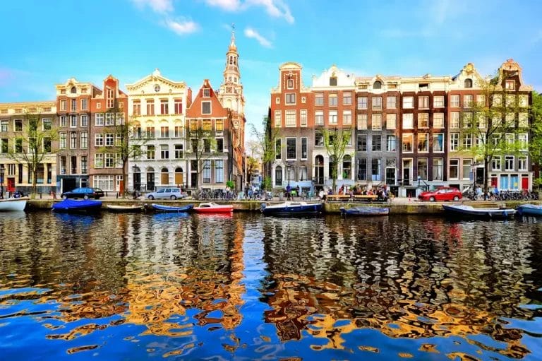 Edifici storici olandesi lungo un canale di Amsterdam, con barche ormeggiate in riva al mare durante un tour.