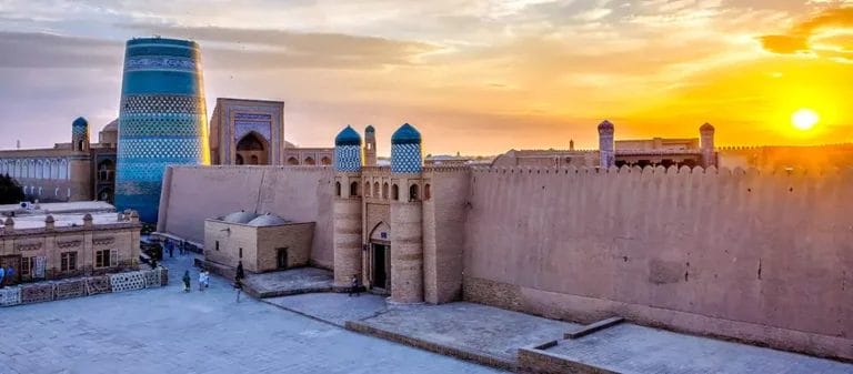 Tramonto su un'antica cittadella dell'Uzbekistan con una caratteristica torre blu e mura fortificate.