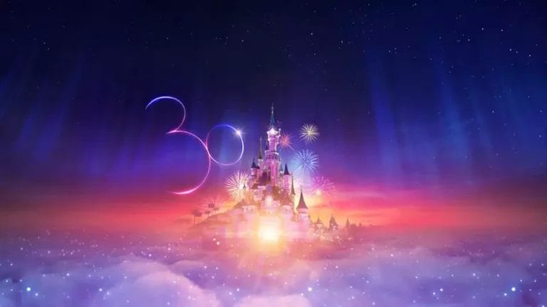 Un magico castello Disney illuminato contro un cielo crepuscolare con fuochi d'artificio e il numero "30" visualizzato in un testo luminoso, a simboleggiare un evento celebrativo.