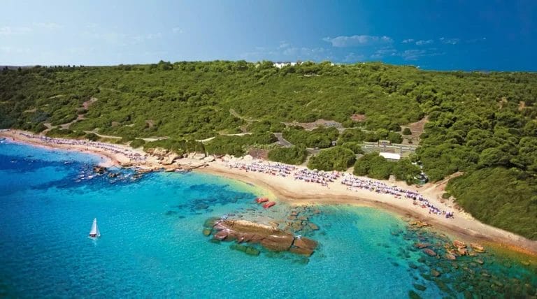 Veduta aerea della spiaggia costiera dell'ASYLA RESORT a Capo Rizzuto, con limpide acque turchesi, una spiaggia sabbiosa e una vegetazione lussureggiante circostante.