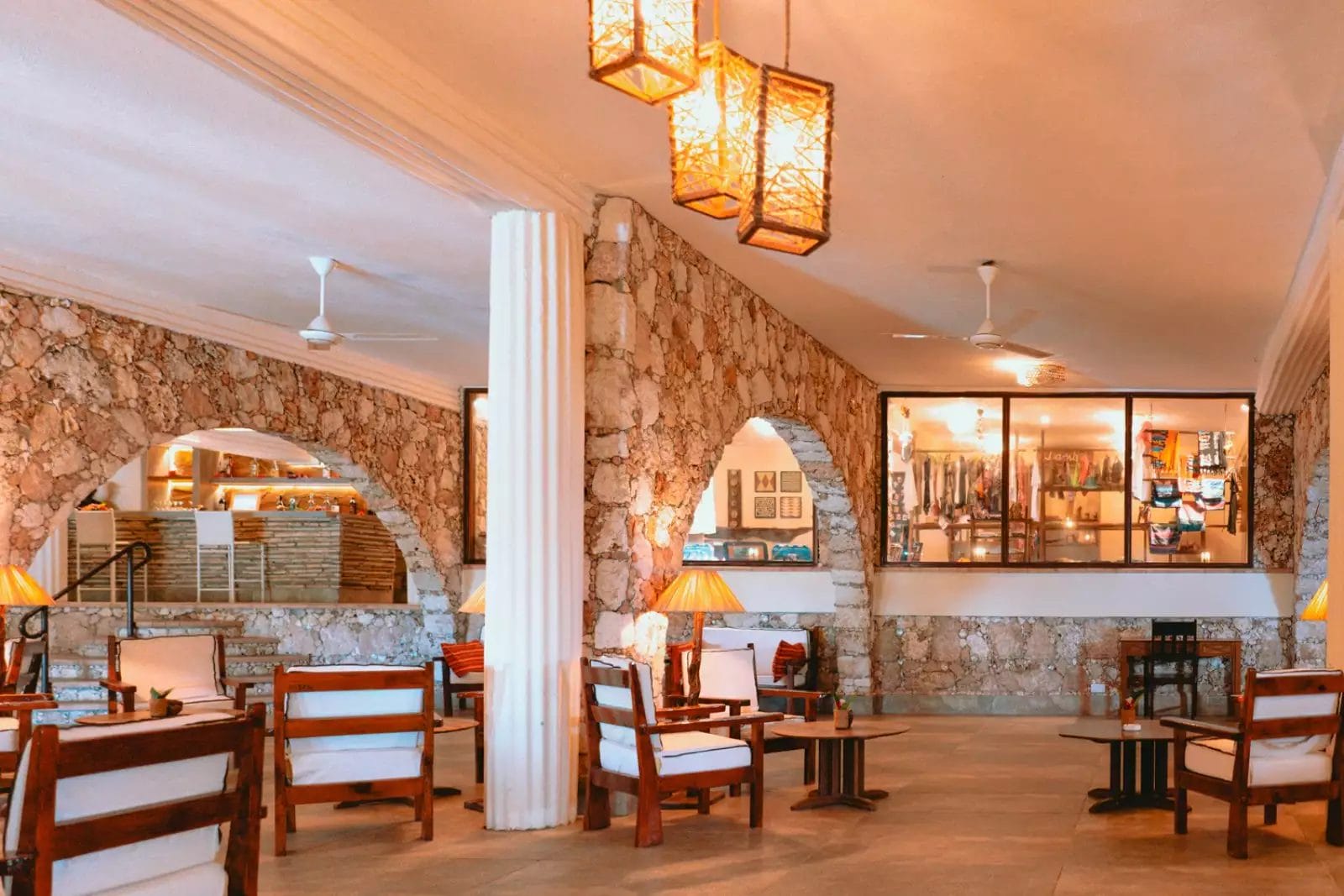 La hall dell'hotel Palumbo vanta pareti in pietra, mobili in legno e luci calde. Lanterne appese e ventilatori a soffitto impreziosiscono l'area spaziosa, creando un'atmosfera da resort dove il dolce suono delle onde sembra appena fuori portata.