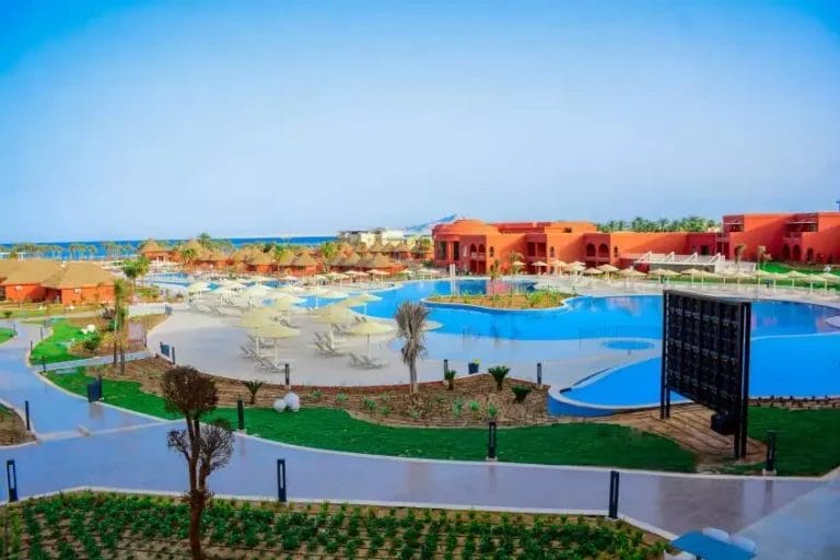 Godetevi la vista mozzafiato del resort Laguna Vista, con numerose piscine all'aperto, sedie a sdraio con ombrelloni, vivaci edifici rossi e un limpido cielo azzurro sullo sfondo.