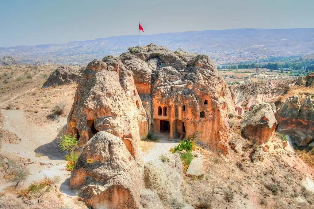 Situate in un paesaggio arido con colline e valli lontane, queste formazioni rocciose vantano aperture scolpite e una bandiera turca in cima, evocando il fascino unico della Cappadocia. Perfette per un'indimenticabile mini avventura turistica.