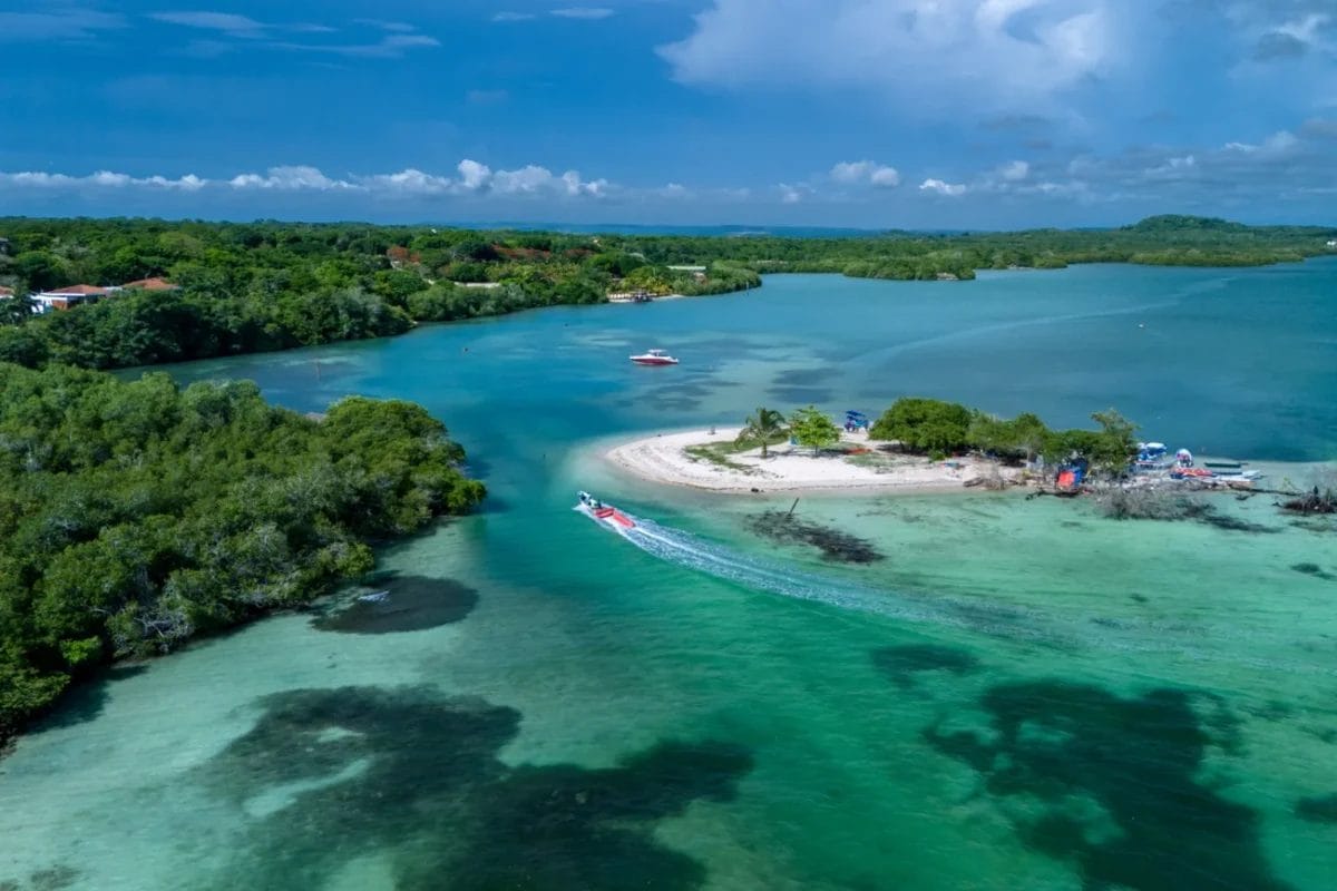 Vista aerea di una piccola isola sabbiosa con barche, circondata da acque turchesi e lussureggianti alberi verdi vicino al resort BRAVO DECAMERON BARU.