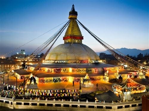Lo stupa di Boudhanath a Kathmandu, Nepal, illuminato da luci colorate al tramonto.