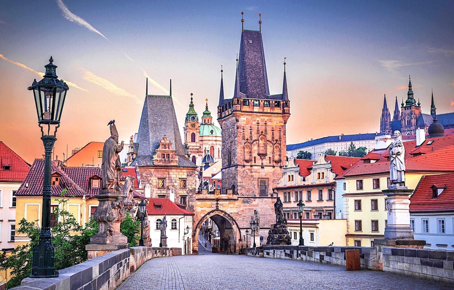 Il Ponte Carlo a Praga all'alba, con statue e torri gotiche storiche sotto un cielo colorato: uno spettacolo imperdibile in qualsiasi tour alla scoperta degli splendidi Castelli della Boemia.