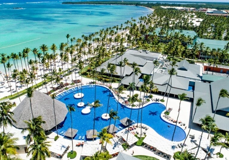 Vista aerea di BARCELO' BAVARO BEACH, un resort tropicale con palme, piscine e splendidi edifici adagiati sulle acque turchesi dell'oceano.