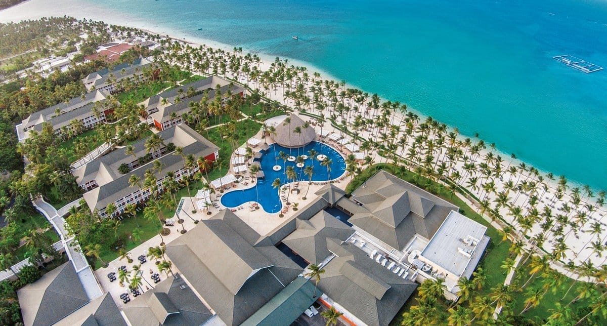 Veduta aerea del resort Barcelo Bavaro Beach con piscine, palme ed edifici adagiati sulle acque turchesi dell'oceano.