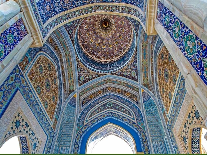 L'intricato soffitto e gli archi di una moschea islamica, riccamente decorati con piastrelle blu, motivi geometrici e disegni floreali ornamentali - come quelli visti in un tour di carovane in Uzbekistan vicino al lago Aydarkul - mostrano una dettagliata maestria e colori vivaci.