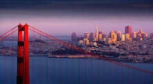 Il Golden Gate Bridge in primo piano e lo skyline di San Francisco sullo sfondo, illuminati dalla calda luce del tramonto: una vista straordinaria durante il vostro TOUR FOREVER WEST attraverso gli STATI UNITI.